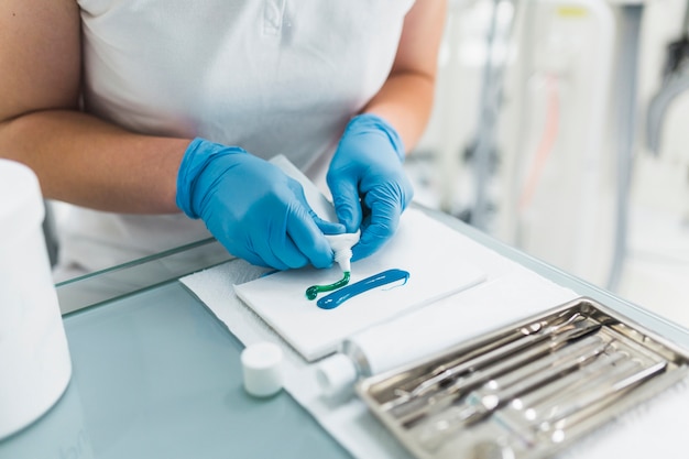 Primer plano de la mano del dentista con material de impresión de silicona verde y azul