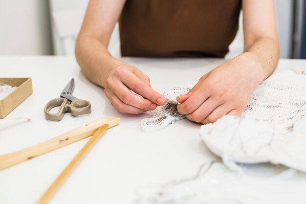 Primer plano de la mano del diseñador de moda trabajando en tela sobre el escritorio de trabajo