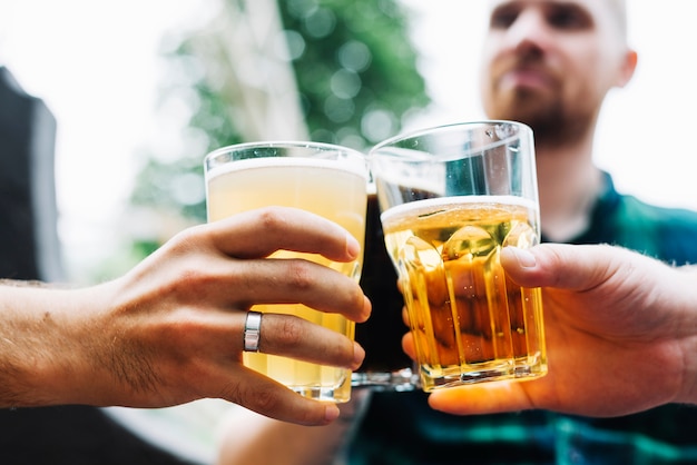 Primer plano de la mano de dos hombres tostado vaso de bebidas alcohólicas