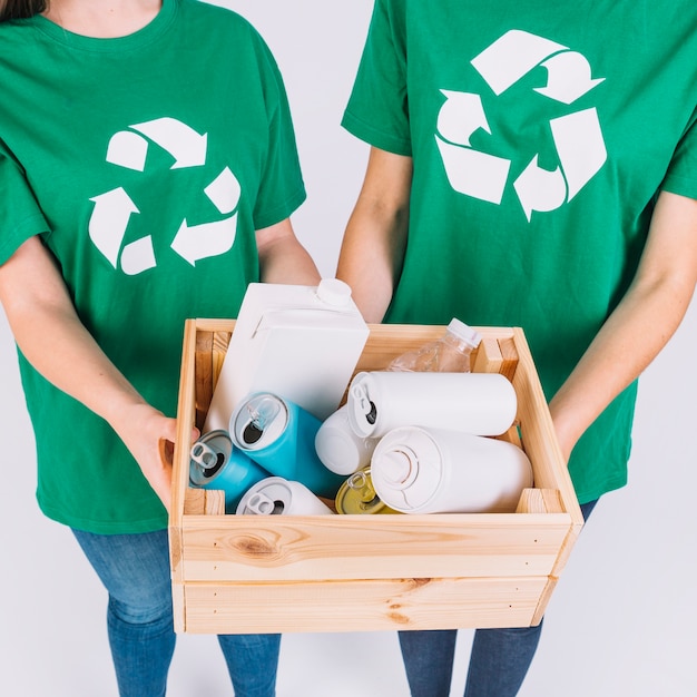 Foto gratuita primer plano de la mano de dos mujeres con caja de madera con artículos de reciclaje