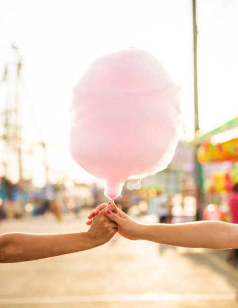 Primer plano de la mano de dos mujeres sosteniendo seda rosa caramelo