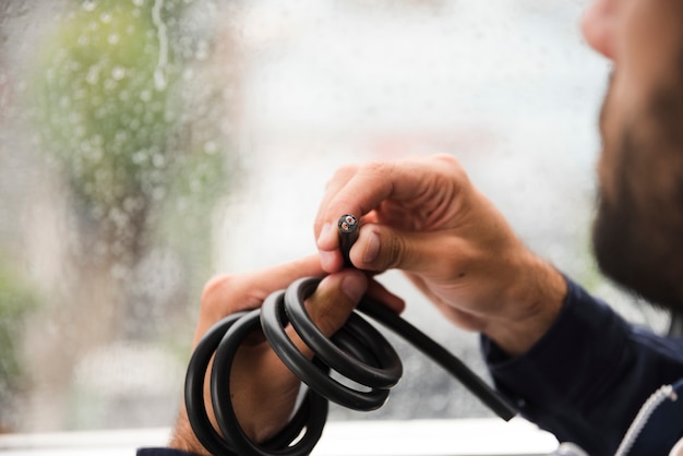 Primer plano de la mano del electricista sosteniendo cable eléctrico negro