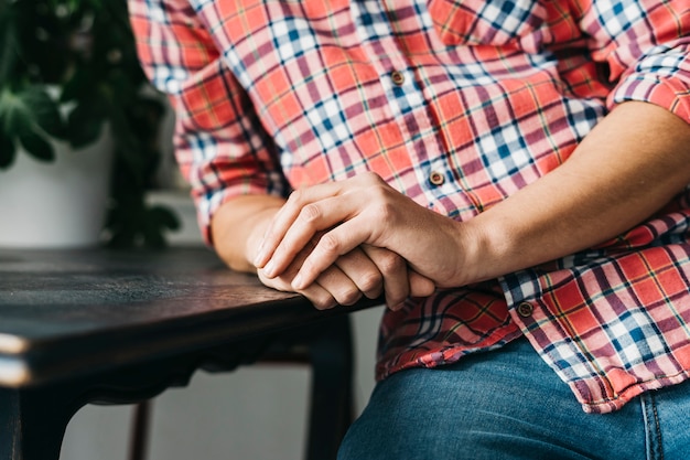 Primer plano de la mano entrelazada del hombre en la mesa de madera