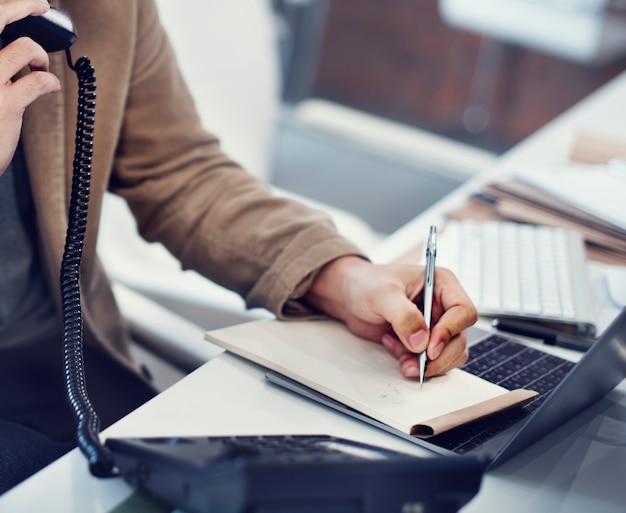 Primer plano de la mano escribiendo nota mientras está en el teléfono