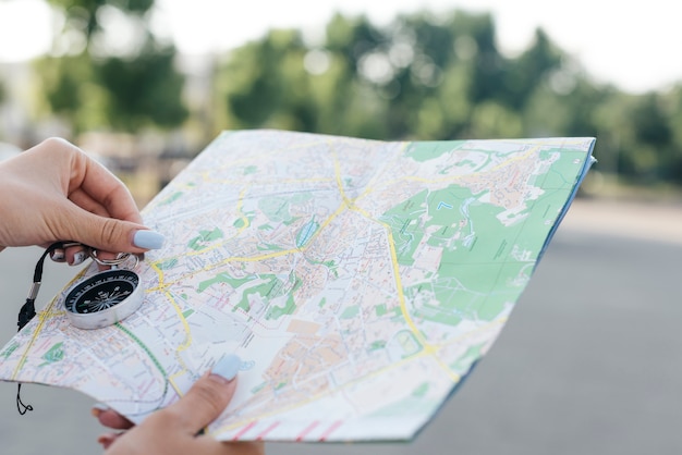 Foto gratuita primer plano de mano femenina sosteniendo mapa y brújula de navegación