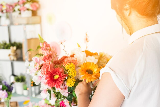 Primer plano de mano florista femenina arreglando flores de colores