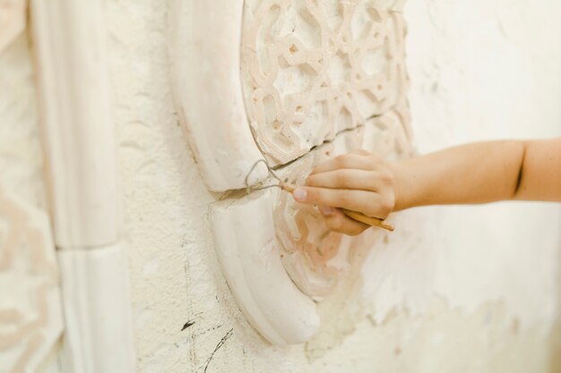 Primer plano de la mano con la herramienta para tallar en la pared