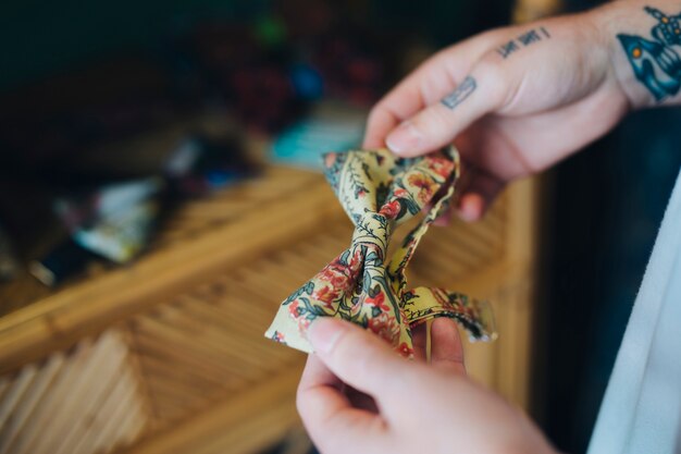 Primer plano de la mano de un hombre con corbata de lazo floral vintage