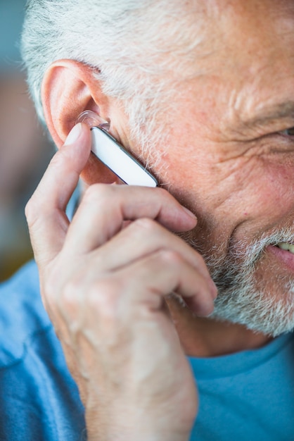 Primer plano de la mano del hombre mayor en el auricular bluetooth en la oreja