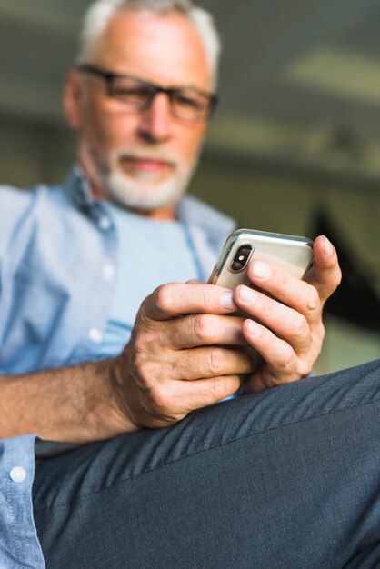 Primer plano de la mano del hombre mayor que sostiene el teléfono móvil