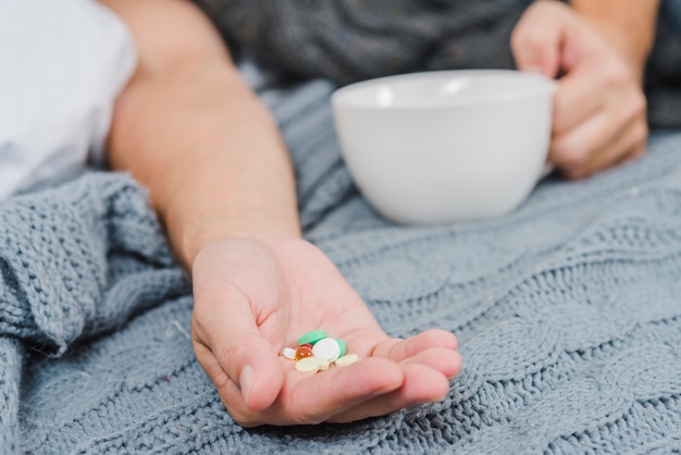 Primer plano de la mano de un hombre mostrando píldoras multicolores