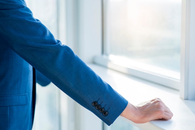 Primer plano de la mano de un hombre de negocios en el alféizar de la ventana