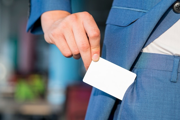 Primer plano de la mano de un hombre de negocios quitando la tarjeta blanca en blanco del bolsillo