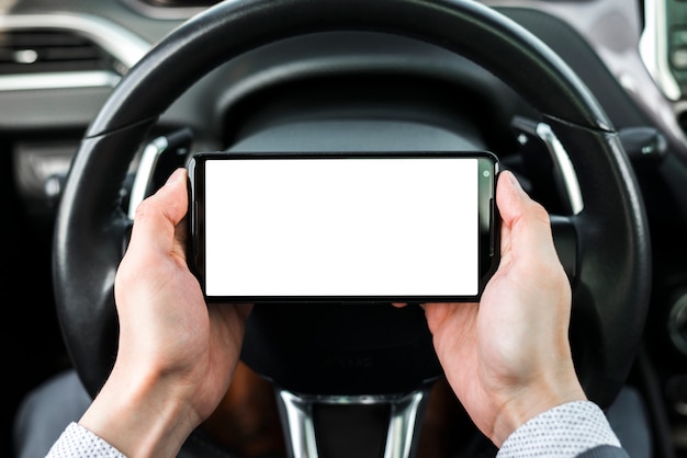 Primer plano de la mano de un hombre de negocios sosteniendo teléfono inteligente delante del volante