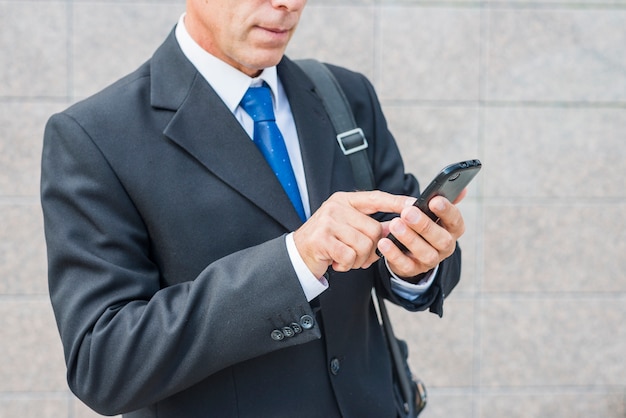 Primer plano de la mano de un hombre de negocios mediante teléfono móvil