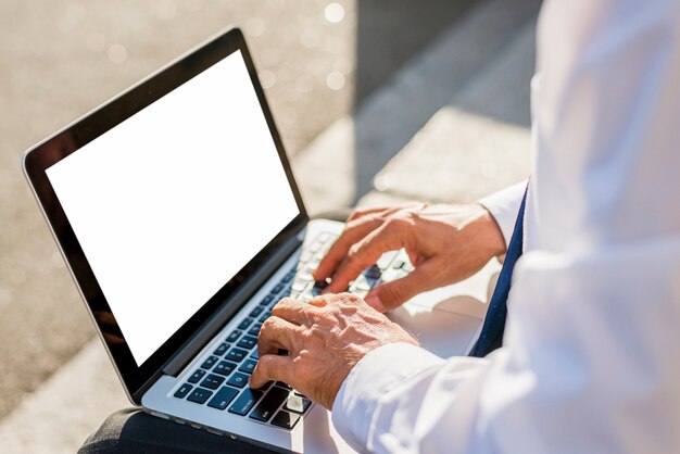 Primer plano de la mano de un hombre de negocios usando una computadora portátil con pantalla blanca en blanco