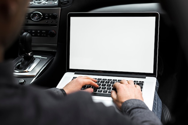 Primer plano de la mano de un hombre de negocios usando laptop sentado en el coche