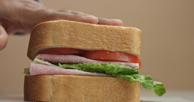 Foto gratuita el primer plano de la mano del hombre presiona el movimiento de acabado del sándwich para la preparación del sándwich