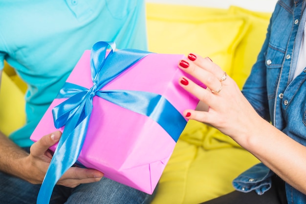 Primer plano de la mano de un hombre que da un regalo sorpresa a su esposa