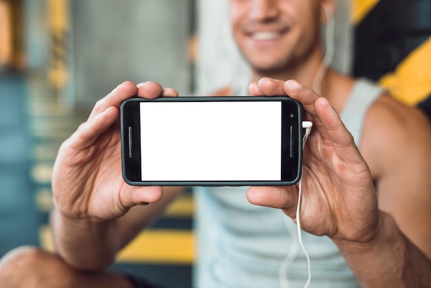 Primer plano de la mano de un hombre que muestra el teléfono celular con pantalla blanca en blanco