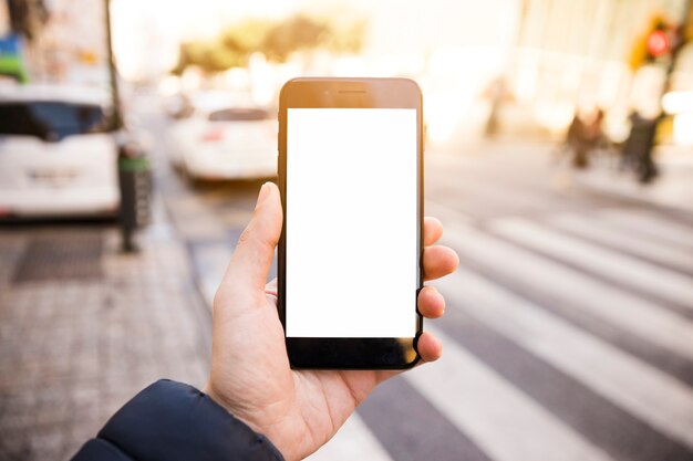 Primer plano de la mano del hombre que muestra el teléfono móvil con pantalla en blanco en la carretera
