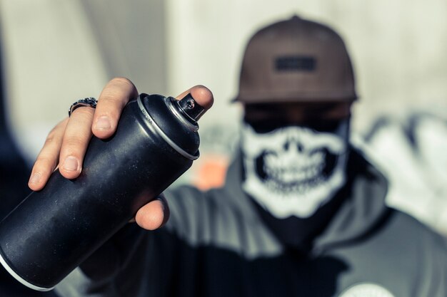 Primer plano de la mano de un hombre que sostiene aerosol negro puede