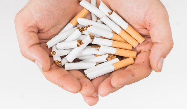 Primer plano de la mano del hombre sosteniendo cigarrillos rotos aislados sobre fondo blanco