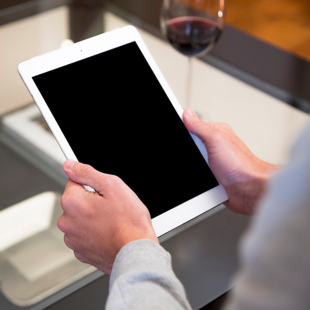 Primer plano de la mano de un hombre sosteniendo una tableta digital con pantalla en blanco