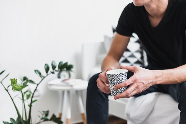 Primer plano de la mano del hombre con taza de cerámica en la mano