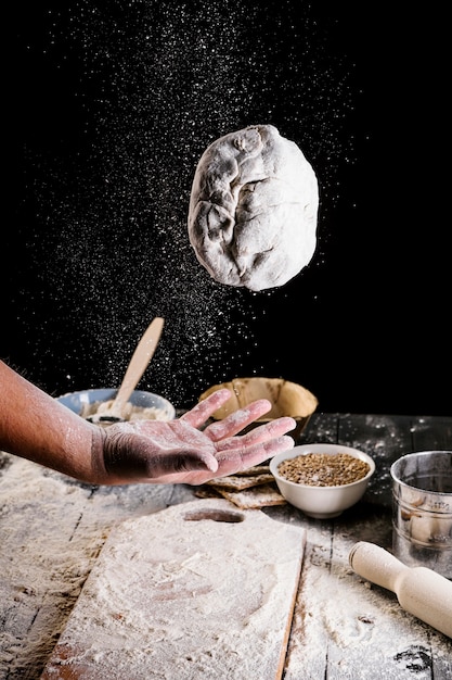 Foto gratuita primer plano de la mano del hombre tirando la masa de pan en el aire
