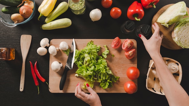 Primer plano de la mano humana con coloridas verduras sobre fondo negro