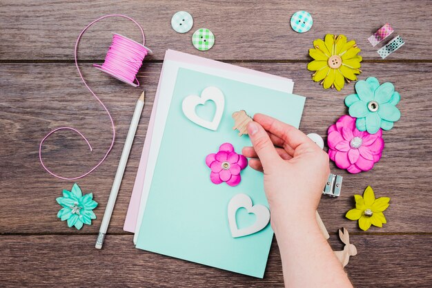 Primer plano de la mano humana que adorna la tarjeta de felicitación en el escritorio de madera