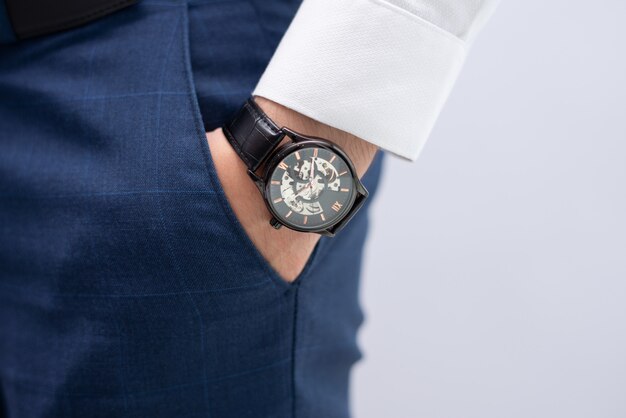 Primer plano de mano masculina en bolsillo con reloj de pulsera moderno y elegante
