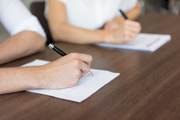 Primer plano de la mano masculina llenando el formulario de solicitud.