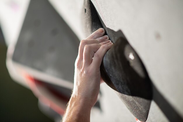 Primer plano de la mano masculina con polvo de talco en la pared de boulder