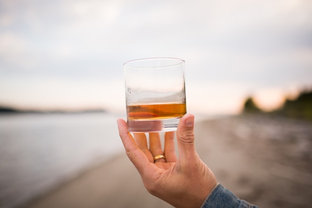 Foto gratuita primer plano de una mano masculina sosteniendo un vaso de whisky