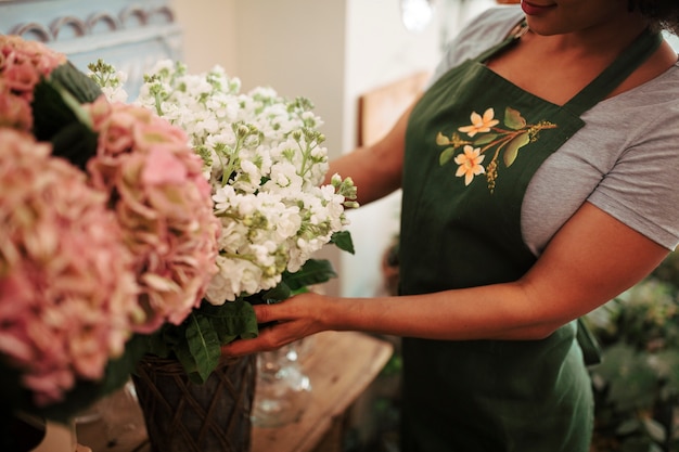 Primer plano de la mano de una mujer arreglando flores en la tienda de flores