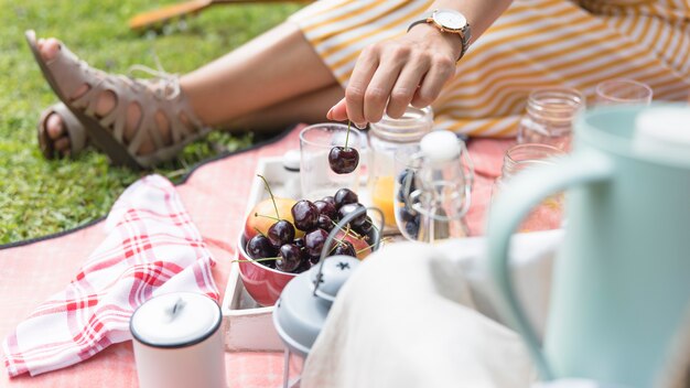 Primer plano de la mano de la mujer con cereza en picnic