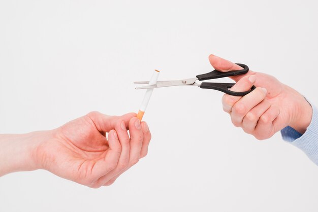 Primer plano de la mano de una mujer cortando un cigarrillo con una tijera de la mano del hombre