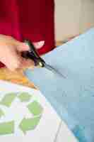 Foto gratuita primer plano de una mano de mujer cortando papel azul con tijeras