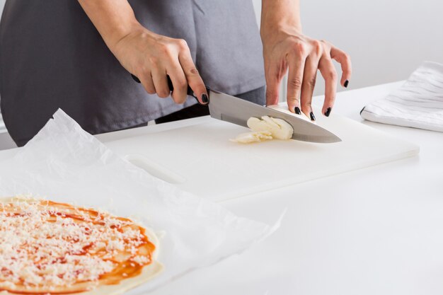 Primer plano de la mano de la mujer cortando el queso con un cuchillo en la tabla de cortar