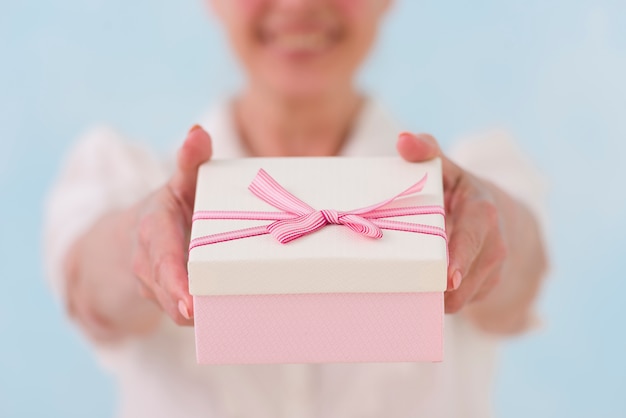 Foto gratuita primer plano de la mano de la mujer dando caja de regalo