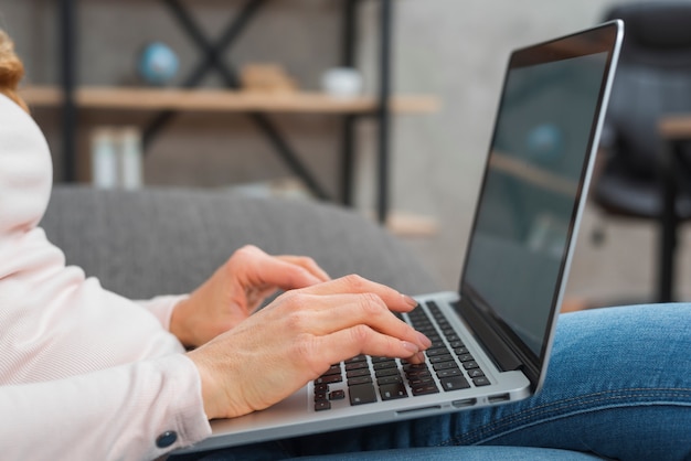 Primer plano de la mano de la mujer escribiendo en la computadora portátil