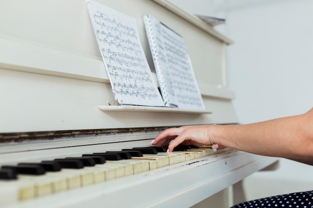 Primer plano de la mano de la mujer joven tocando el piano