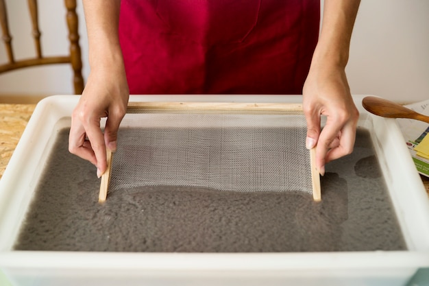 Foto gratuita primer plano de la mano de una mujer poniendo moho en la pulpa de papel