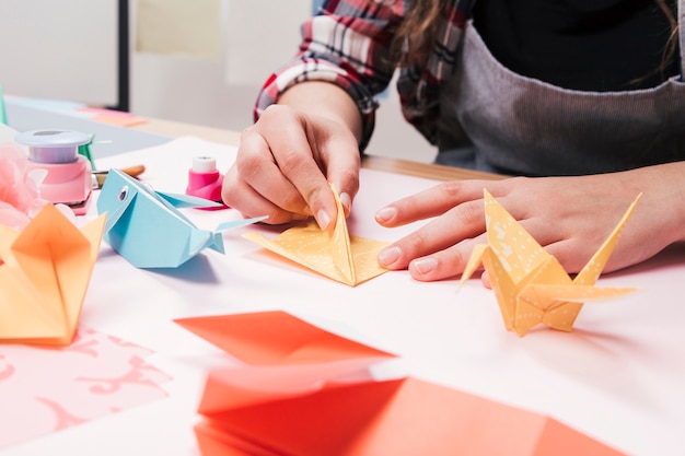 Primer plano de la mano de la mujer que hace arte creativo del arte usando el papel del origami