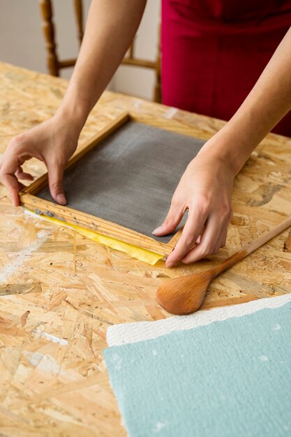 Primer plano de la mano de una mujer que hace el papel en el escritorio de madera