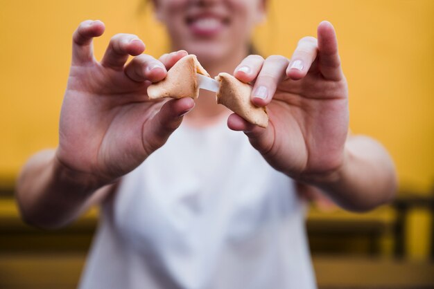 Primer plano de la mano de la mujer que muestra el mensaje en la galleta de la fortuna