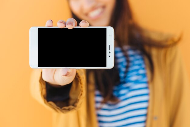 Primer plano de la mano de una mujer que muestra un teléfono móvil con pantalla en blanco