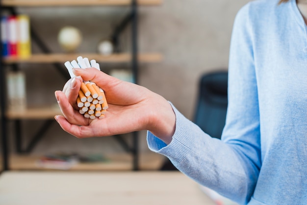 Primer plano de la mano de la mujer que sostiene el manojo de cigarrillo